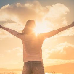 Young woman with hands up the morning sun light finding happiness, peace and hope in nature